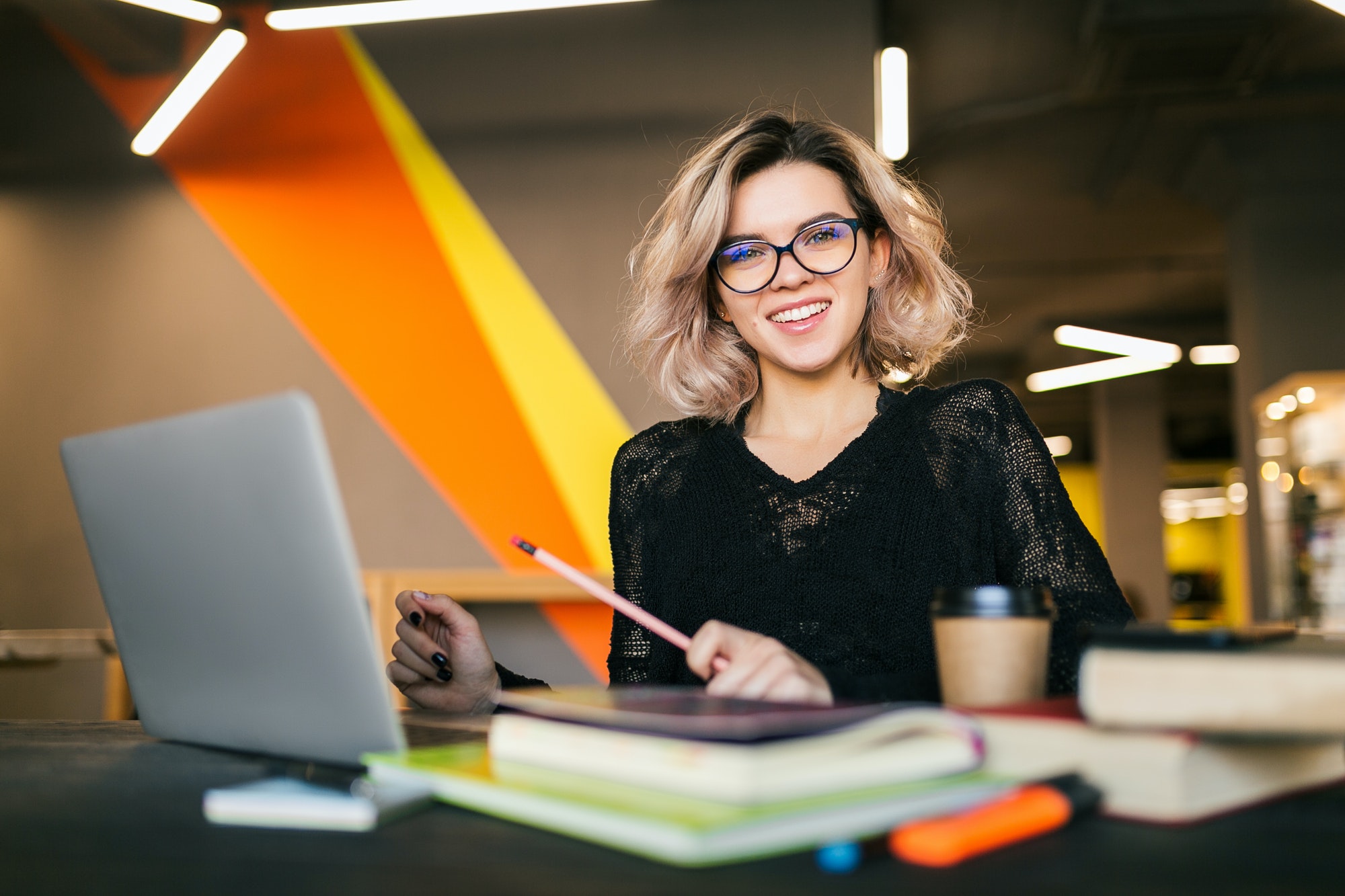 young woman working on laptop in co-working office young woman working on laptop in co-working office